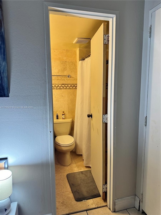 bathroom with a shower with shower curtain and toilet