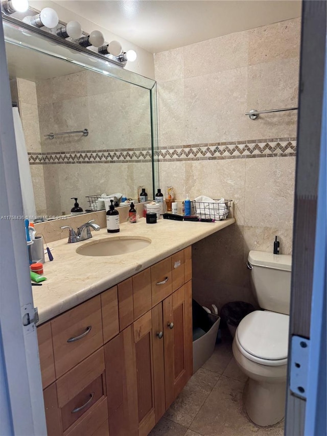 bathroom with toilet, tile patterned floors, tile walls, and vanity