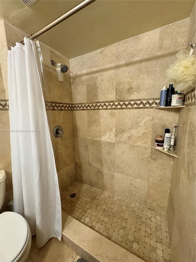 full bath with a tile shower and toilet