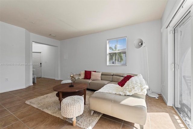 living room featuring light tile patterned flooring, visible vents, and baseboards