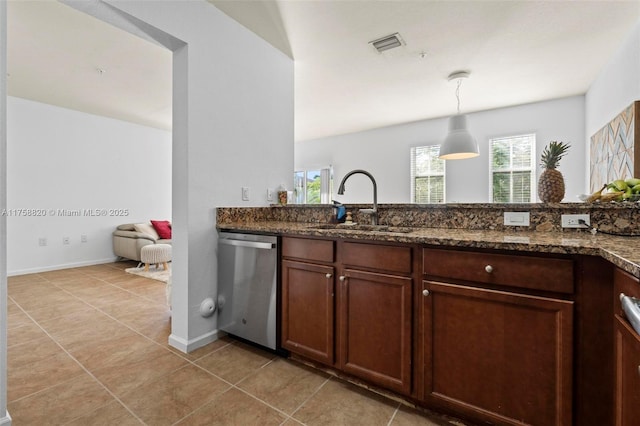 kitchen with pendant lighting, a sink, stainless steel dishwasher, dark stone counters, and light tile patterned flooring