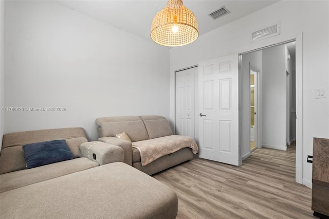 living area featuring visible vents, light wood-style flooring, and baseboards