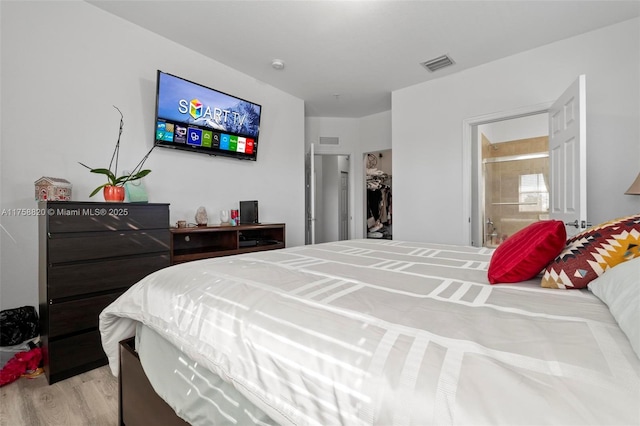 bedroom featuring ensuite bath, visible vents, and light wood finished floors