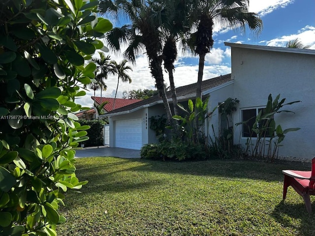 view of property exterior with a yard, concrete driveway, an attached garage, and stucco siding