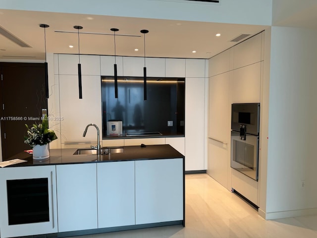 kitchen featuring beverage cooler, dark countertops, modern cabinets, white cabinetry, and a sink