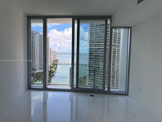 unfurnished room featuring a water view and expansive windows