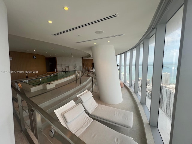 hall with a wall of windows, recessed lighting, a view of the beach, and a water view