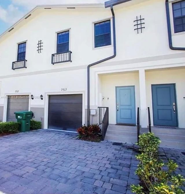 view of front of home featuring stucco siding, an attached garage, and decorative driveway