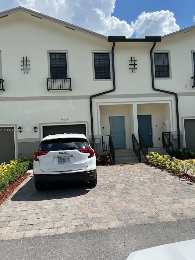 view of front of home featuring stucco siding, decorative driveway, and a garage