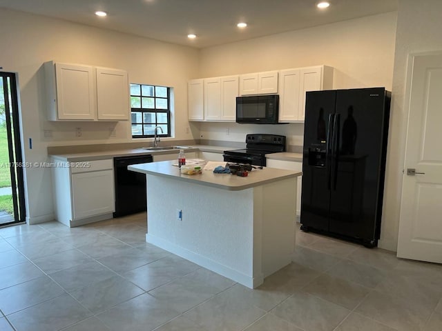 kitchen featuring a kitchen island, light countertops, white cabinets, black appliances, and a sink