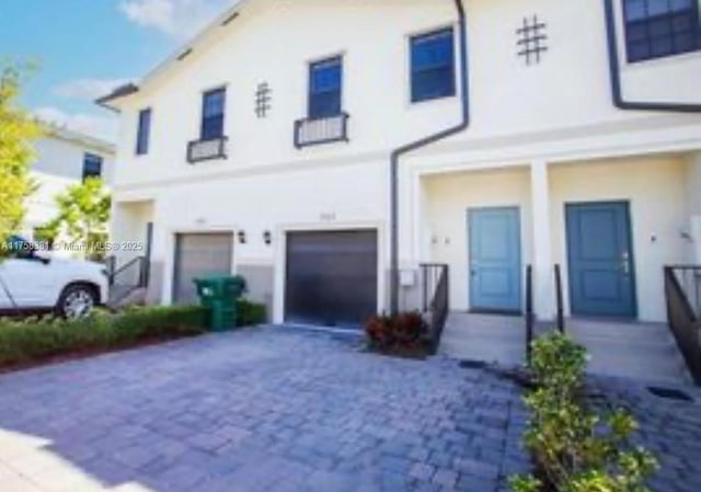 view of front of house with decorative driveway, a garage, and stucco siding