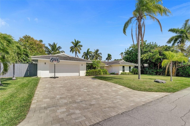 single story home featuring a garage, fence, decorative driveway, a front yard, and stucco siding