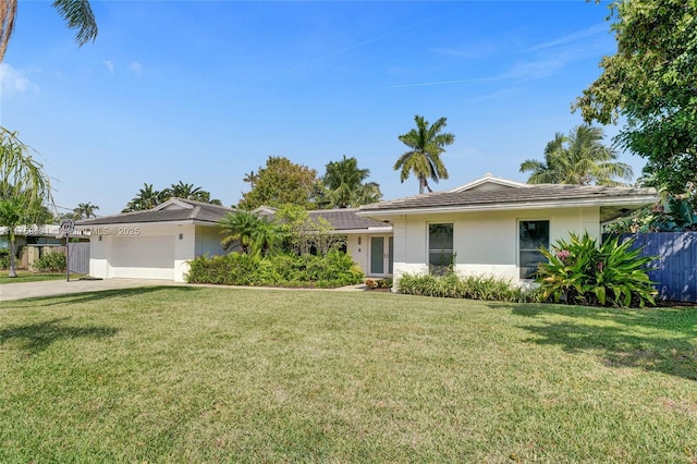 ranch-style house with a front yard, an attached garage, fence, and stucco siding