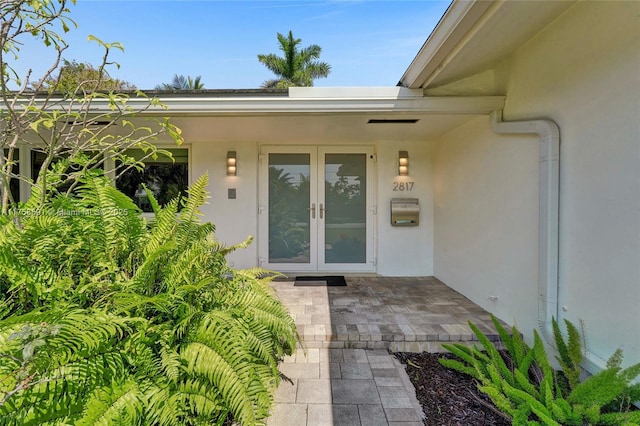 entrance to property featuring french doors and stucco siding