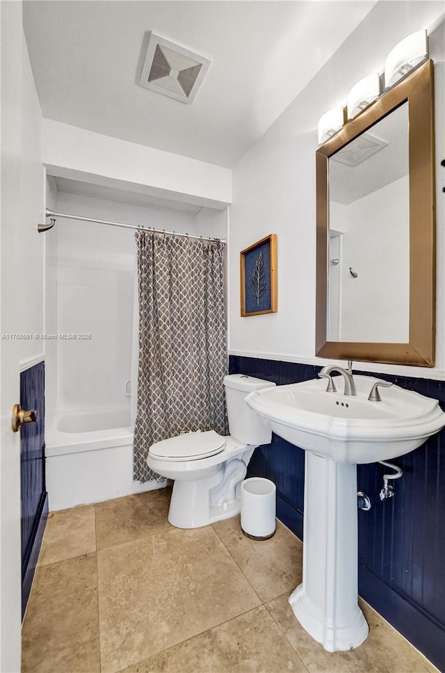 bathroom with visible vents, toilet, shower / tub combo, a sink, and tile patterned floors