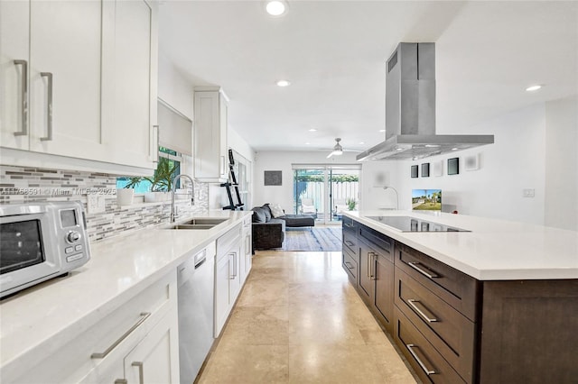 kitchen with island range hood, light countertops, stainless steel dishwasher, white cabinetry, and a sink