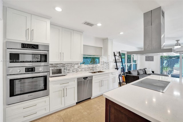 kitchen featuring stainless steel appliances, a wealth of natural light, visible vents, and island range hood