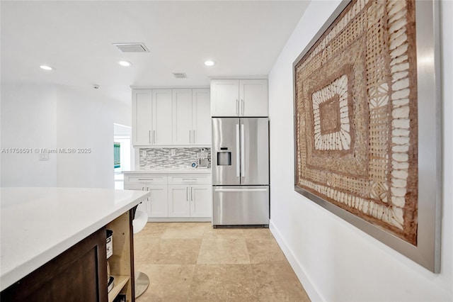 kitchen featuring stainless steel refrigerator with ice dispenser, recessed lighting, light countertops, backsplash, and white cabinets