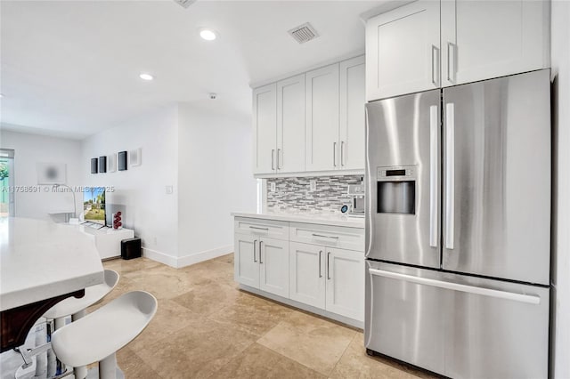 kitchen featuring recessed lighting, visible vents, white cabinets, decorative backsplash, and stainless steel fridge