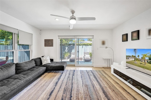 living area with a ceiling fan and baseboards