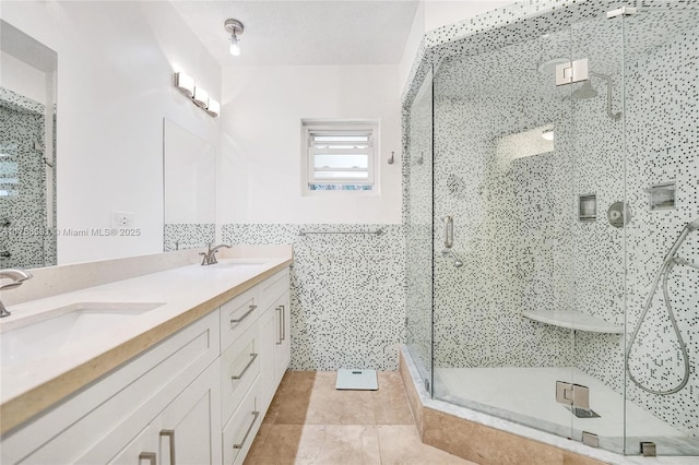 full bathroom featuring tile patterned flooring, a shower stall, tile walls, and a sink