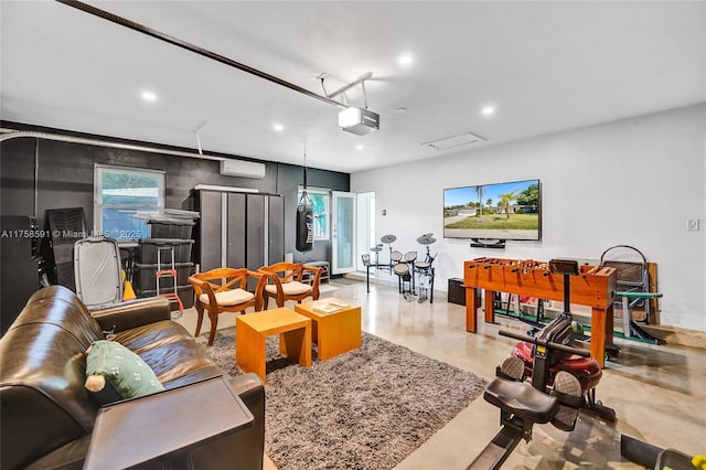 living area with finished concrete floors, recessed lighting, a wall unit AC, and a garage