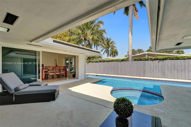 view of swimming pool featuring a patio area, a pool with connected hot tub, and fence