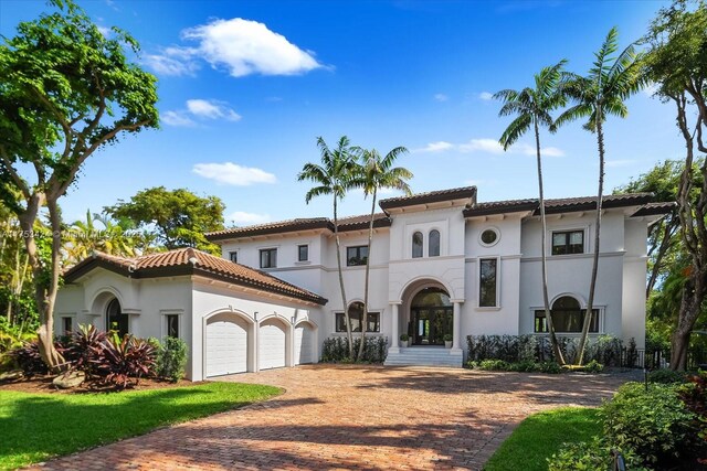 mediterranean / spanish-style house with a tile roof, decorative driveway, a garage, and stucco siding