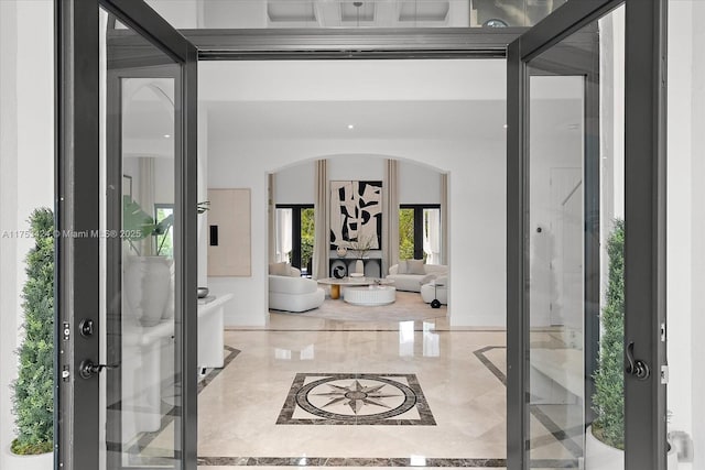 foyer featuring french doors, arched walkways, and marble finish floor