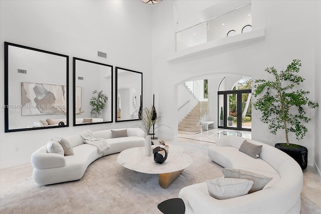 living room with stairway, a high ceiling, and visible vents