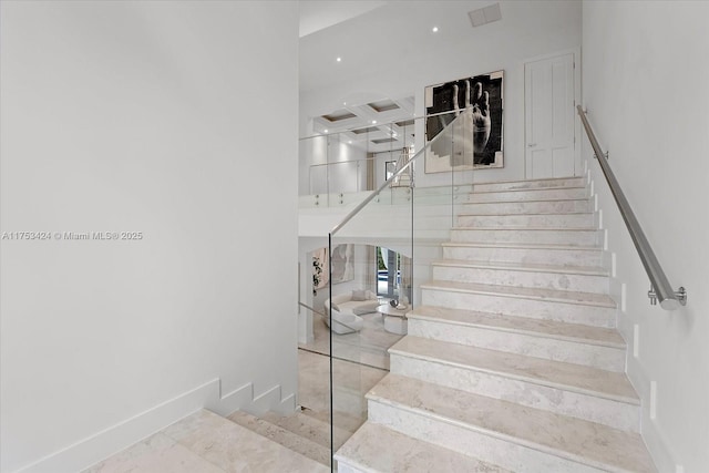 stairs featuring a towering ceiling, baseboards, and coffered ceiling