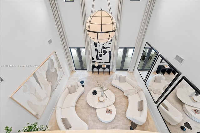 living area with visible vents, french doors, and a high ceiling