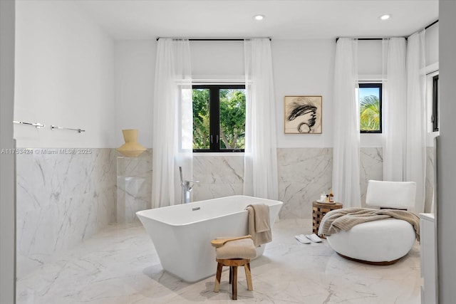 full bathroom with recessed lighting, a freestanding tub, tile walls, and marble finish floor