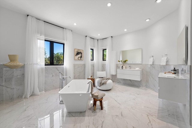 full bathroom featuring recessed lighting, marble finish floor, a freestanding bath, and vanity