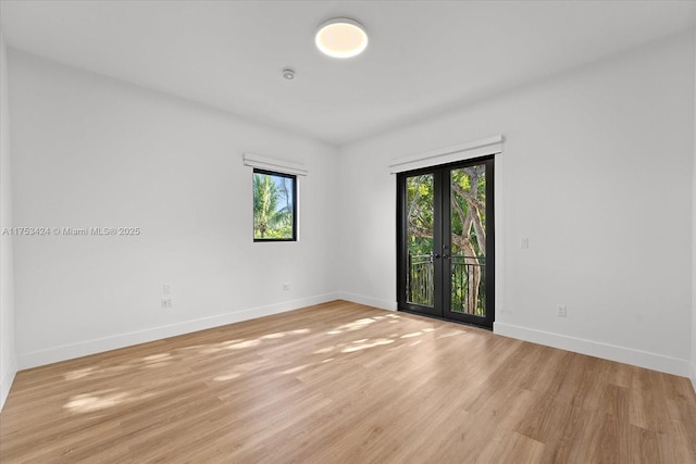 unfurnished room featuring french doors, baseboards, and light wood finished floors