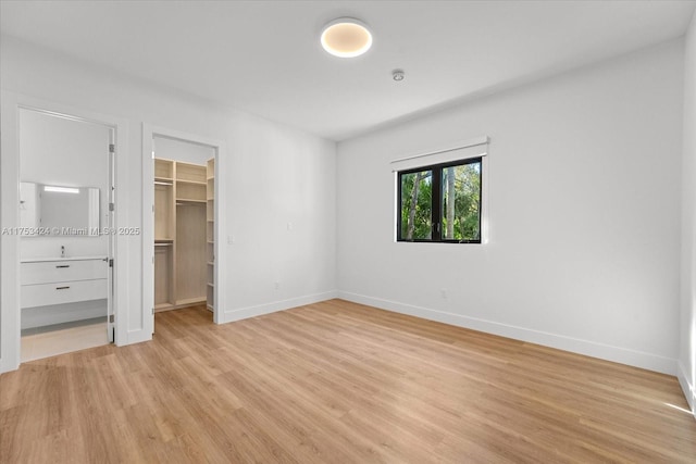 unfurnished bedroom with light wood-type flooring, baseboards, a closet, and a spacious closet