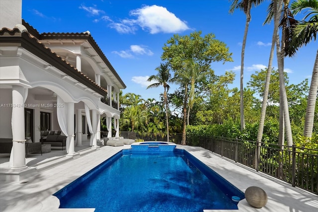 view of swimming pool with a patio, fence, a pool with connected hot tub, and an outdoor hangout area