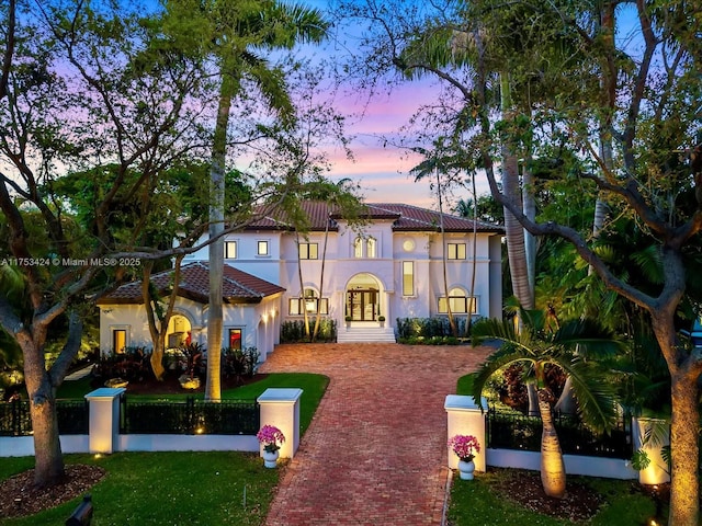 view of front facade featuring a tile roof, a fenced front yard, and stucco siding