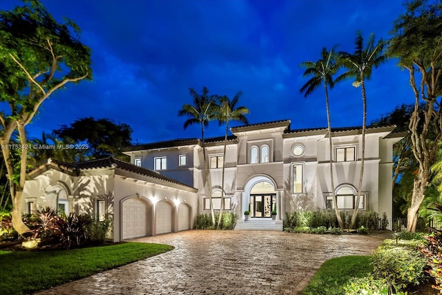 mediterranean / spanish-style home with french doors, decorative driveway, a garage, and stucco siding