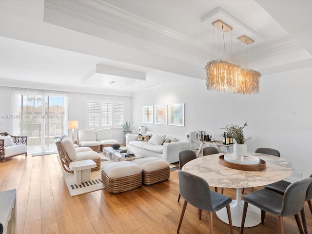 living area with light wood-style flooring, a tray ceiling, and crown molding