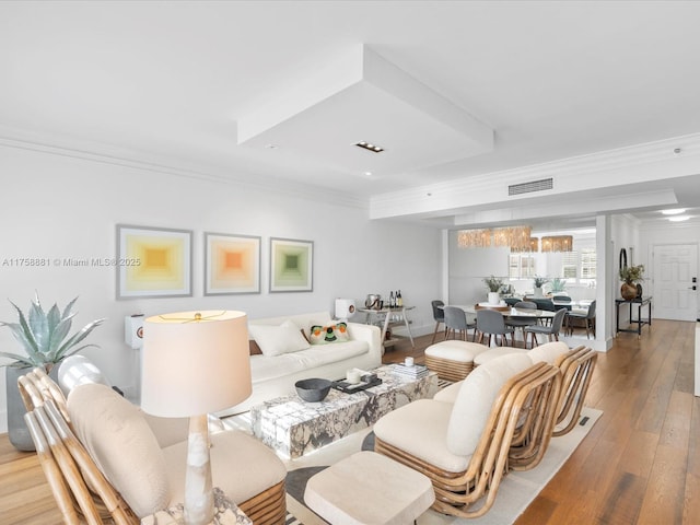 living area with visible vents, crown molding, and light wood-style flooring