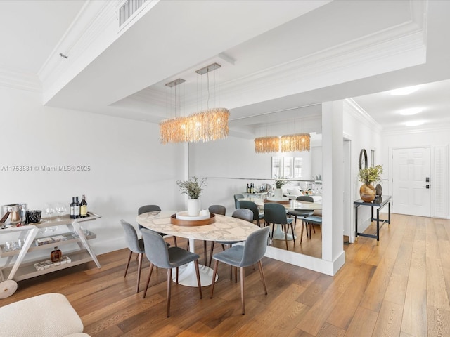 dining room with a chandelier, visible vents, wood-type flooring, a raised ceiling, and crown molding