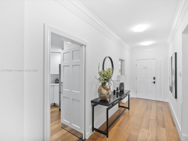 foyer entrance featuring baseboards, light wood-type flooring, and crown molding