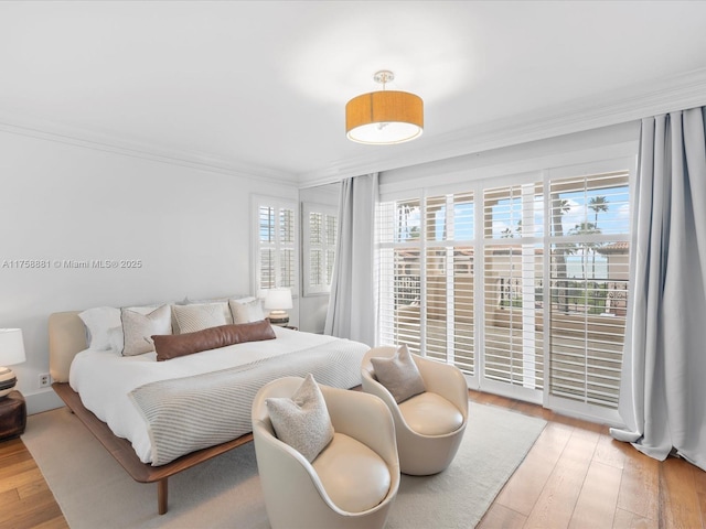 bedroom with ornamental molding, access to exterior, and hardwood / wood-style floors