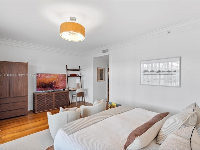 bedroom featuring visible vents, ornamental molding, and wood finished floors