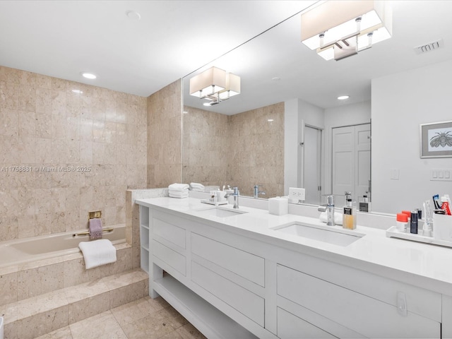 full bath featuring double vanity, tiled bath, visible vents, and a sink