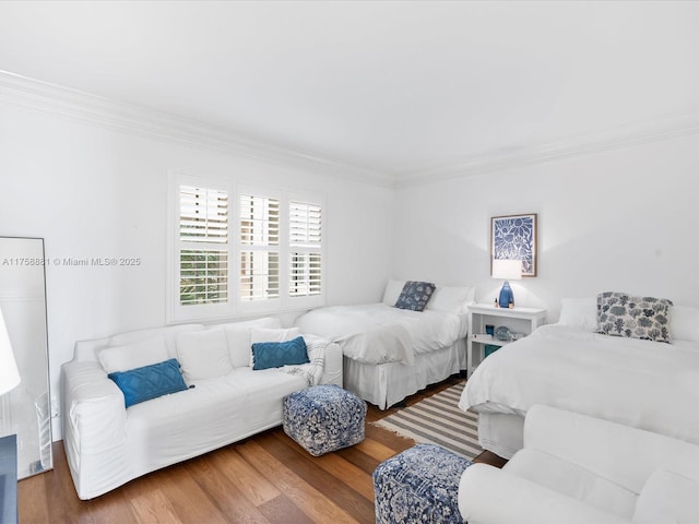 bedroom with ornamental molding and wood finished floors