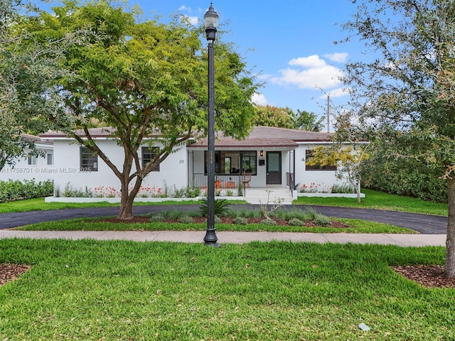 single story home featuring covered porch, a front yard, and stucco siding