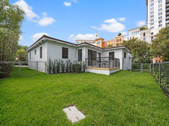 rear view of property with a fenced backyard, stucco siding, a gate, and a lawn