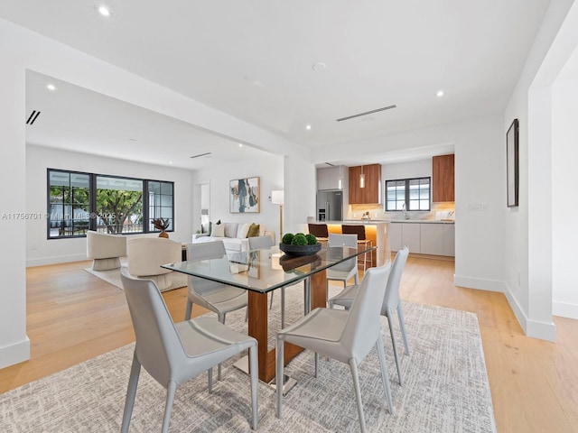 dining room with baseboards, light wood finished floors, and recessed lighting